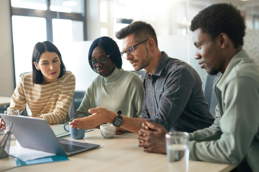 Digitale Strategieberatung für verschiedene Branchen Vier Personen besprechen gemeinsam ein Projekt an einem Laptop.