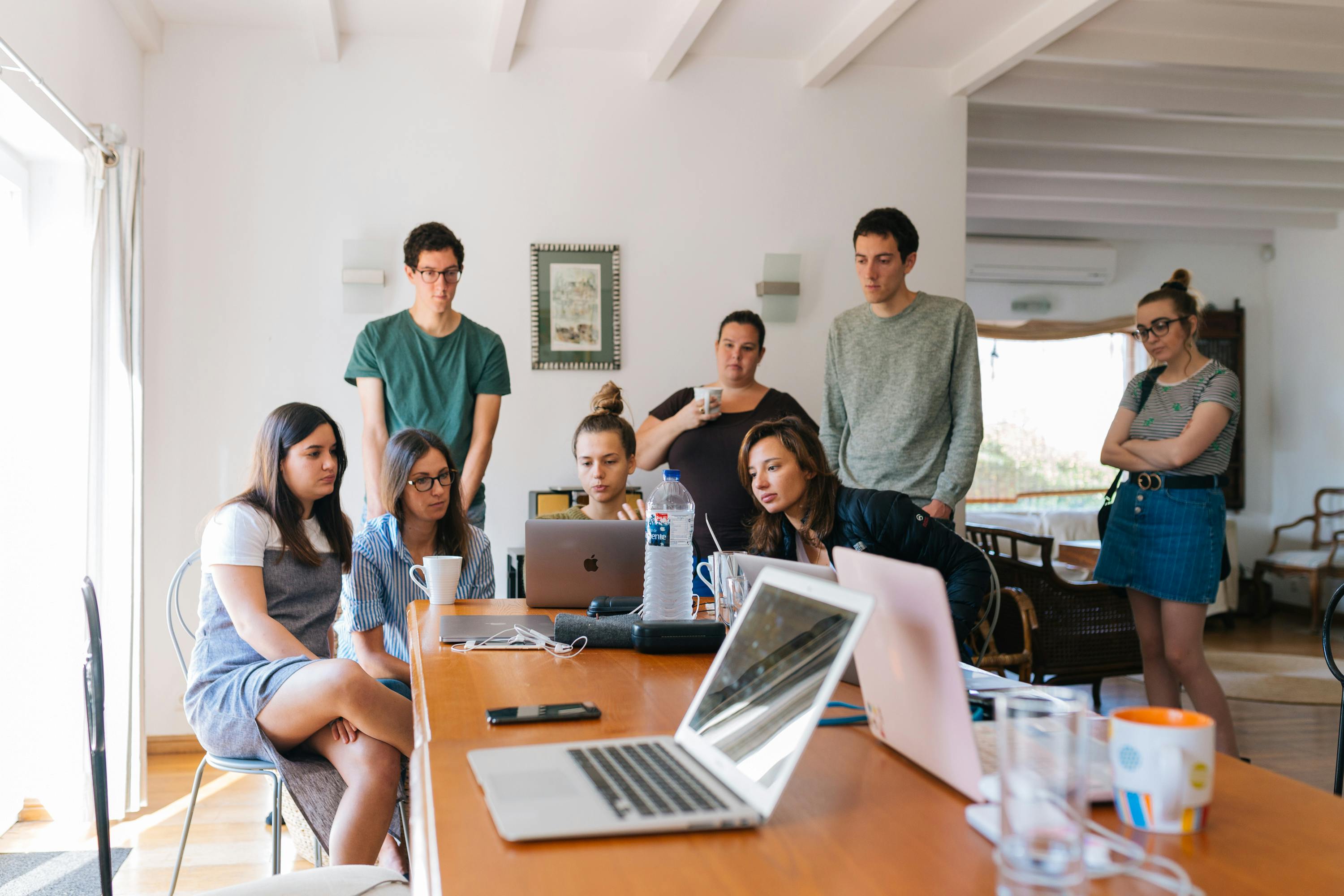 Team bespricht gemeinsam ein digitales Projekt an einem Tisch mit Laptop.